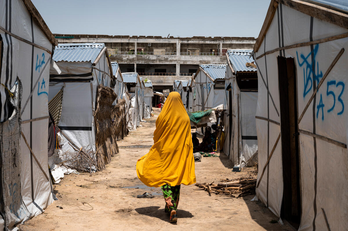 Miriam*, 16, walks past shelters in a camp for displaced people in Borno, Nigeria [Photo credit: Yvonne Etinosa/Save the Children]